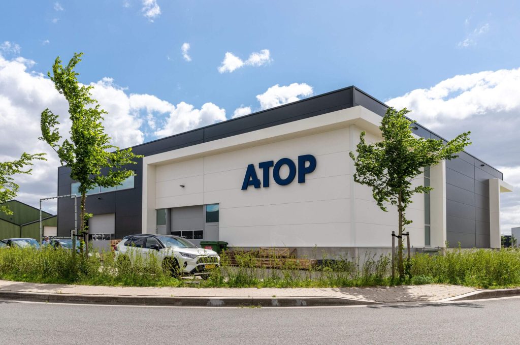 Bedrijfsgebouw met logo ATOP en geparkeerde auto