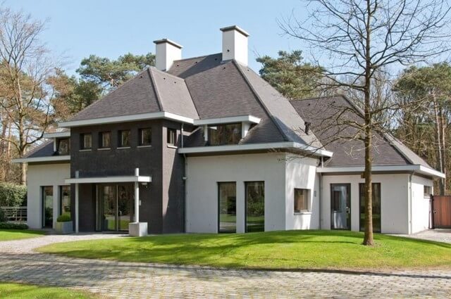 Modern huis met puntdak in bosrijke omgeving.