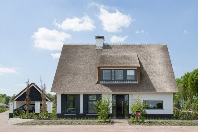 Moderne woning met rieten dak in landelijke omgeving.