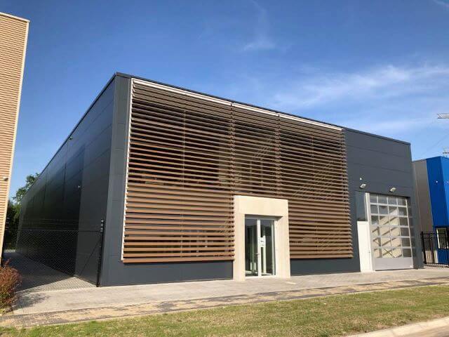 Modern industrieel gebouw met louvres en glazen ingang.