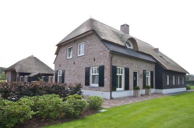 Traditionele bakstenen woning met rieten dak.