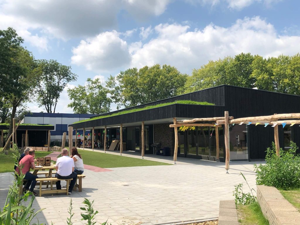 Buitenruimte bij modern gebouw met mensen aan picknicktafel.