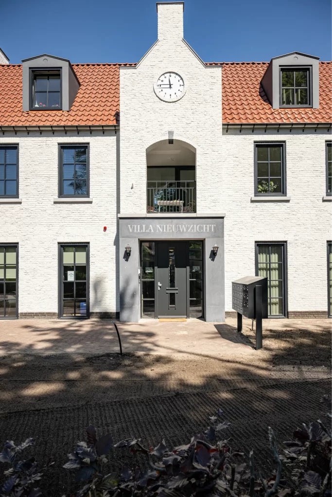 Voorkant van witte villa met rode dakpannen.