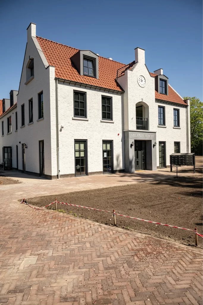 Wit gebouw met rode dakpannen en klokgevel.