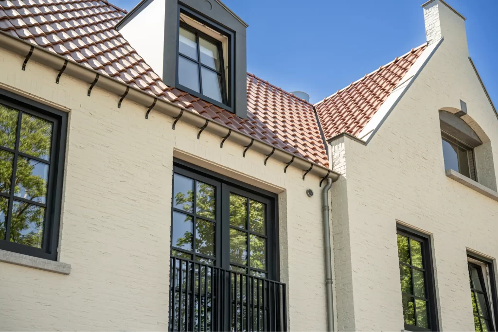 Wit huis met zwarte kozijnen en rood dak.