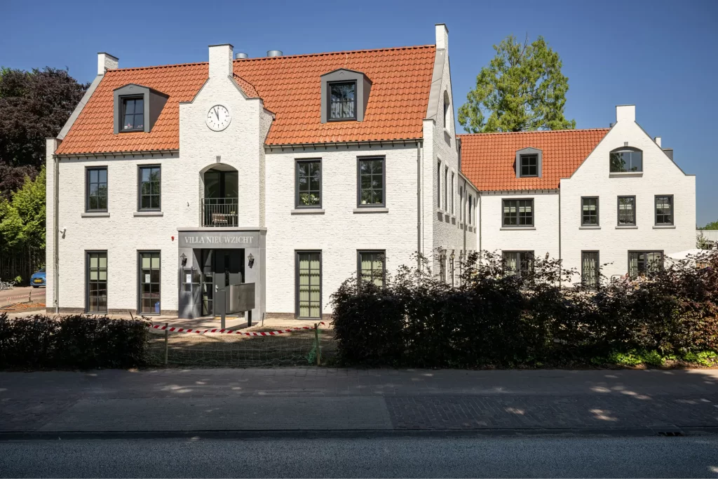 Wit gebouw met rode dakpannen en klok.