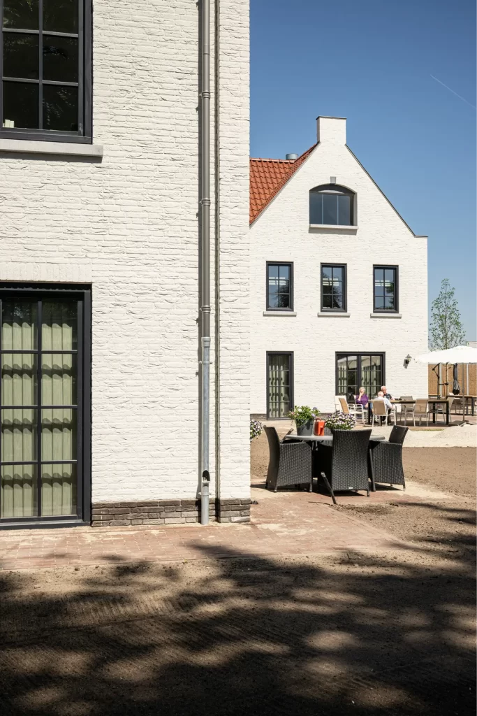 Wit huis met terras onder blauwe lucht.