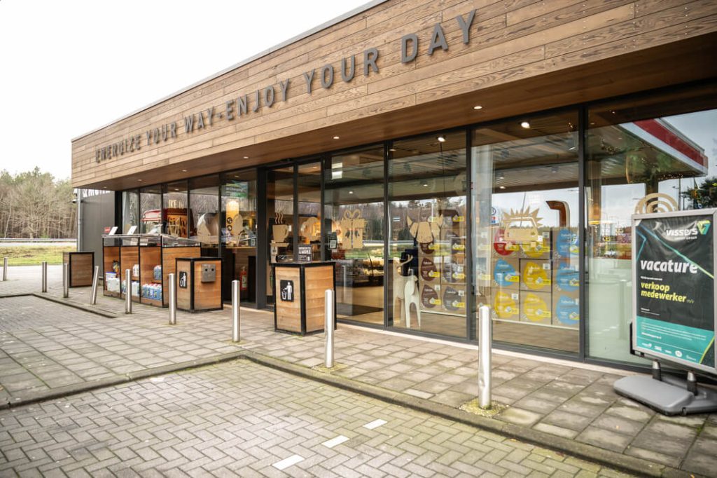 Tankstation met winkel en vacaturebord buiten.