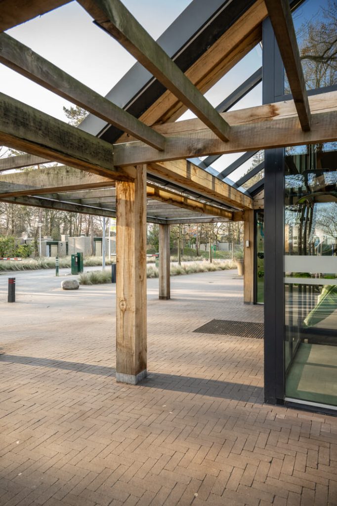 Moderne houten overkapping bij gebouwingang in park