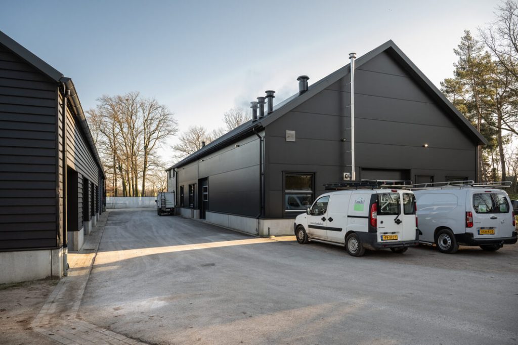 Zwarte bedrijfsgebouwen met bestelwagens op de oprijlaan.