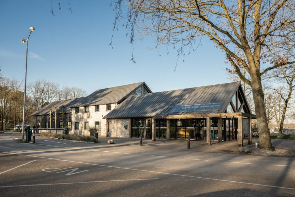 Natuurvriendelijk gebouw met zonnepanelen en parkeerplaats.