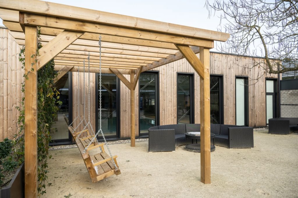 Houten schommel onder pergola, moderne buitenruimte.