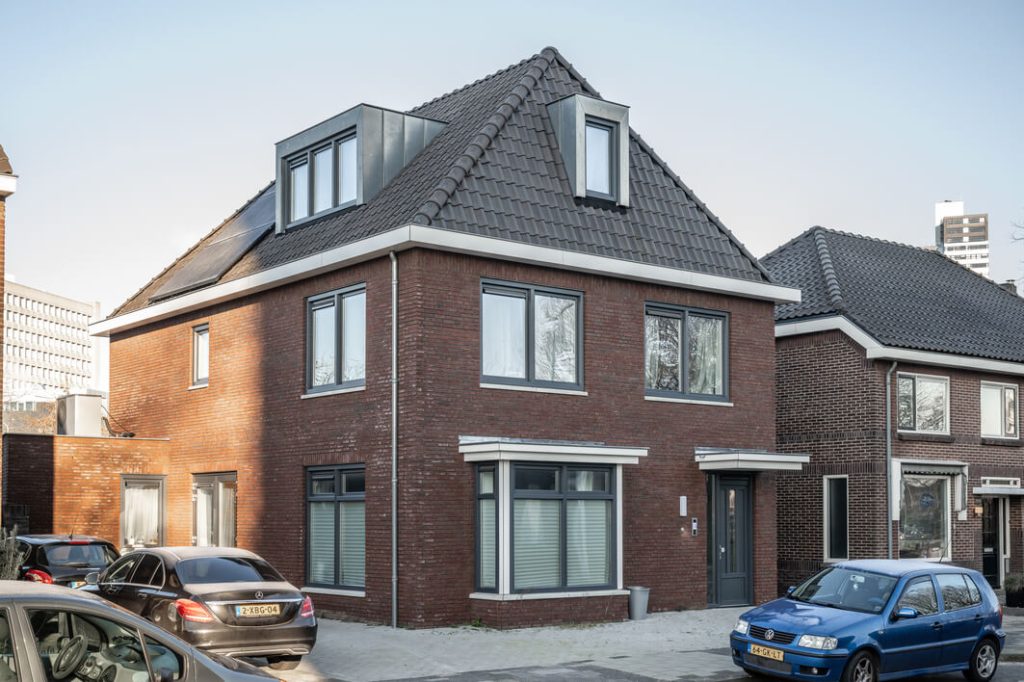 Moderne bakstenen woning met dakramen en geparkeerde auto's