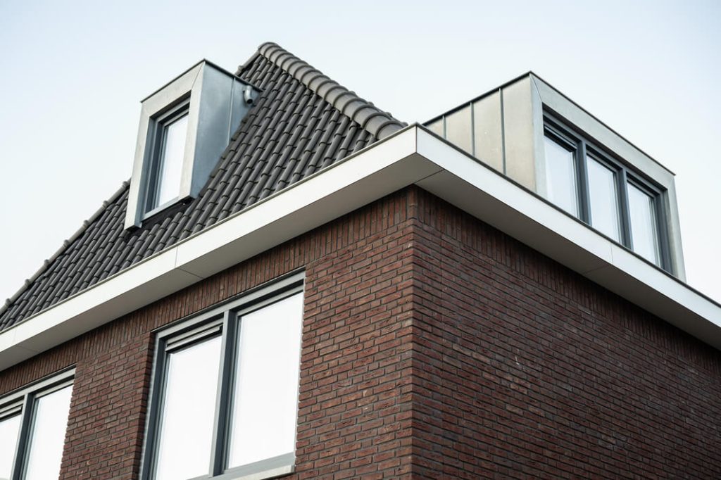 Modern huis met bruine bakstenen en dakramen.