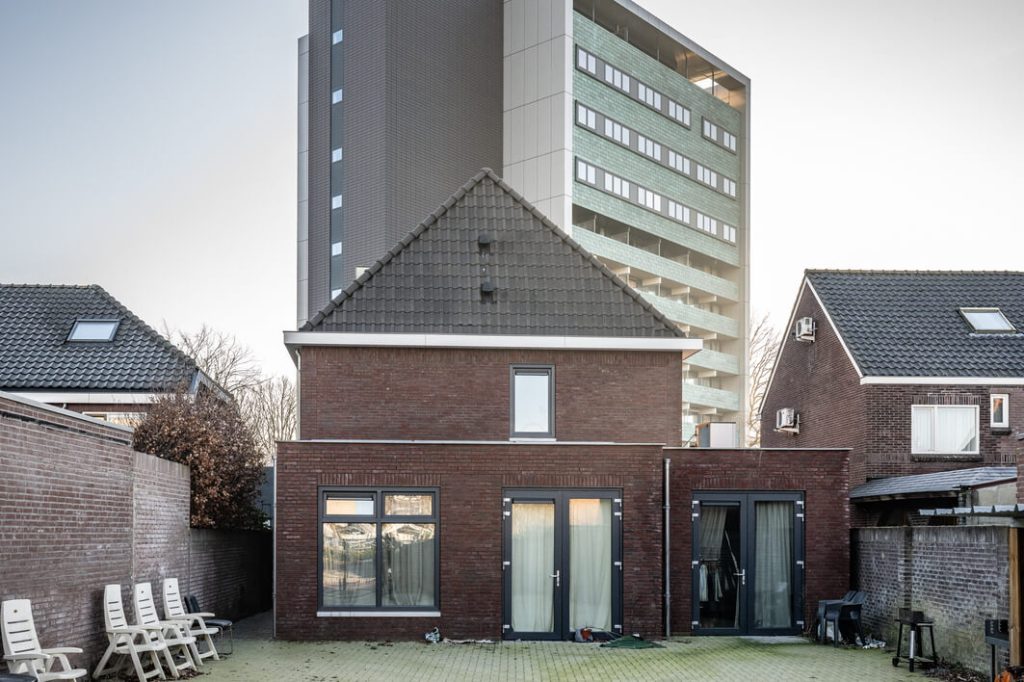 Oud huis naast modern gebouw in achtertuin