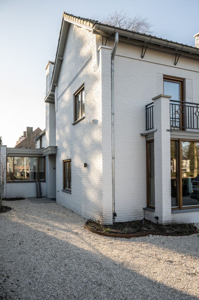 Witte bakstenen huis met ramen en balkon.