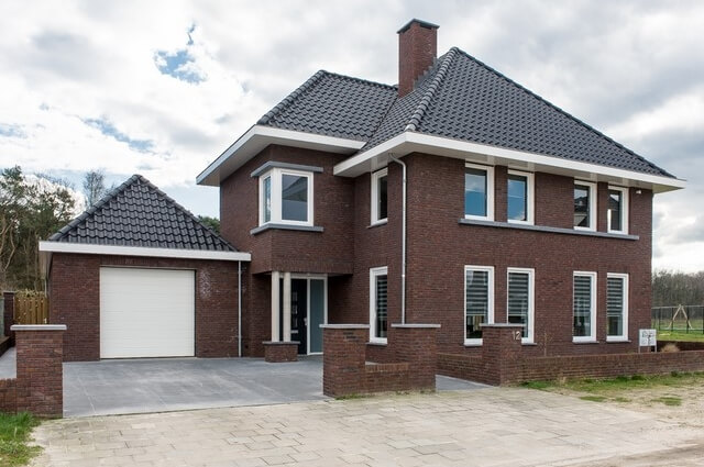 Bakstenen huis met omliggende tuin en oprit.