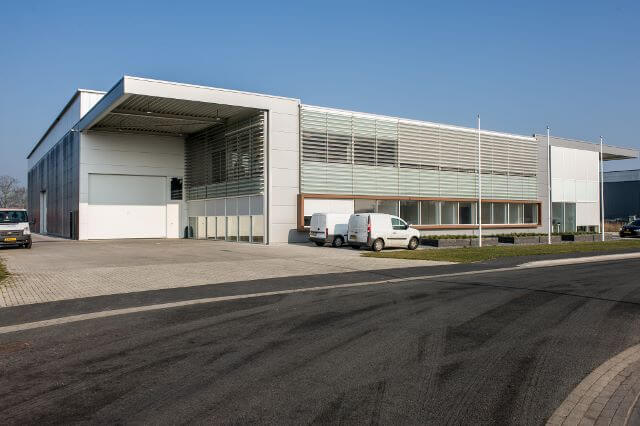 Modern industrieel gebouw met voertuigen op parkeerplaats.