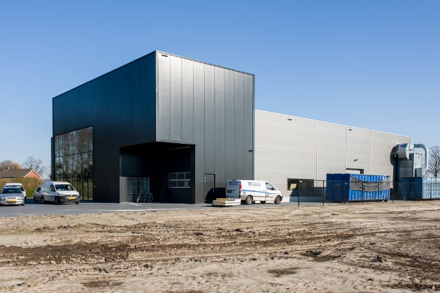 Modern bedrijfsgebouw met parkeerplaats in de zon.