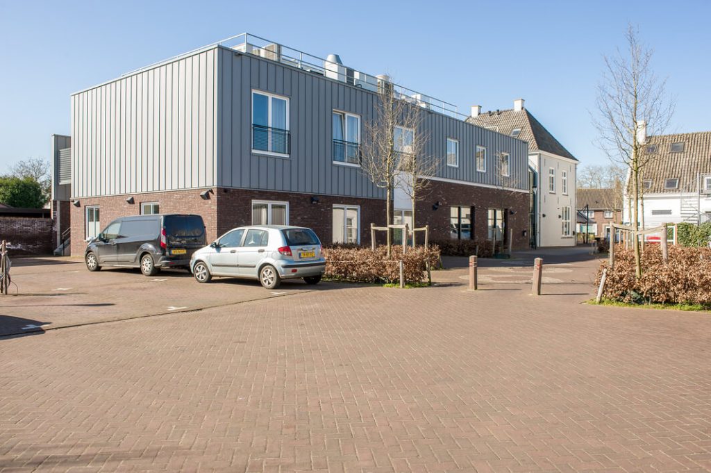 Modern gebouw met parkeerplaats op zonnige dag