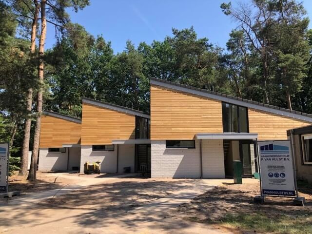 Moderne houten woningen in bosrijke omgeving.