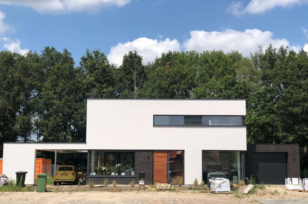 Modern huis met groot raam en auto onder carport.