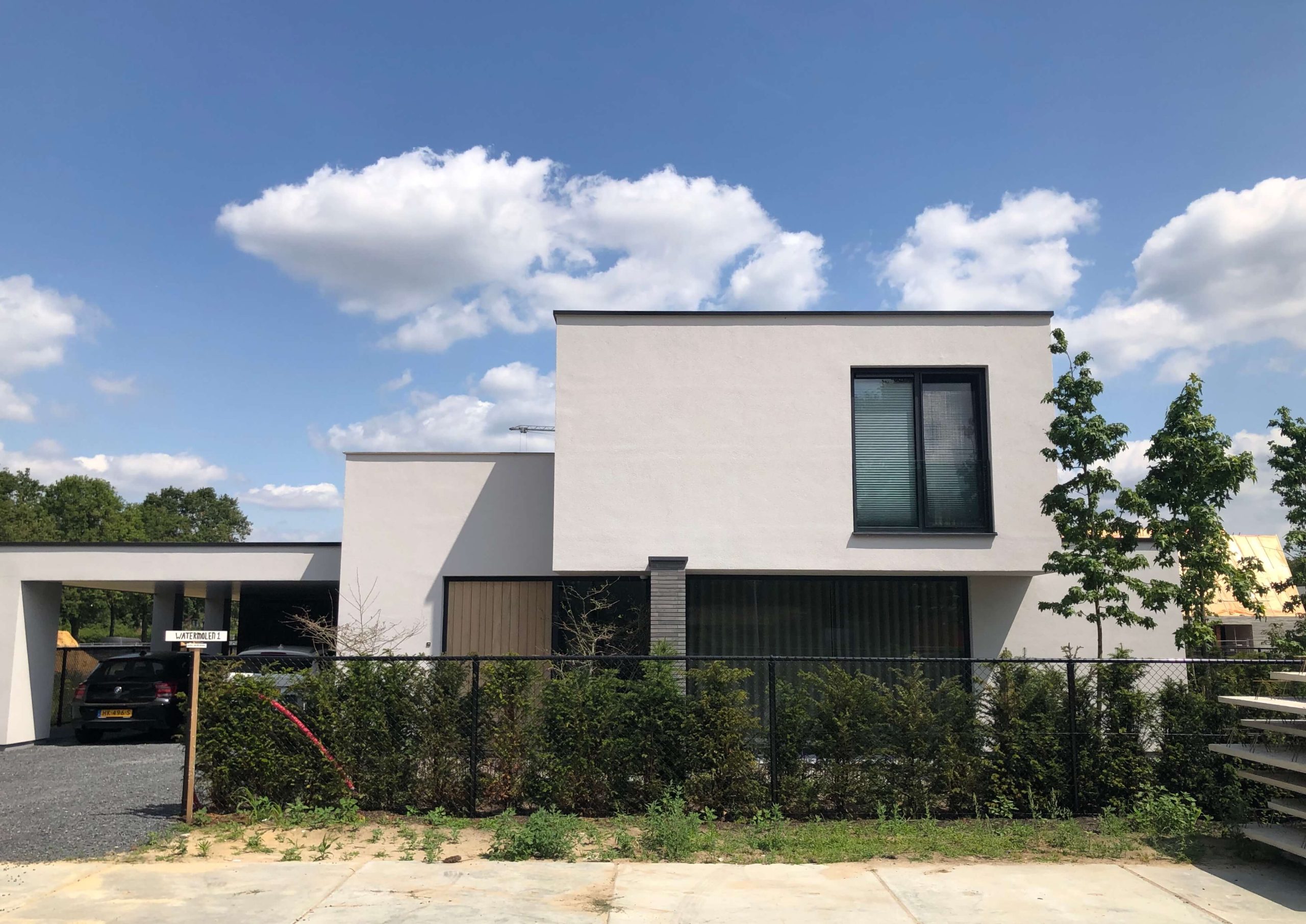 Moderne, witte woning met hek en bomen