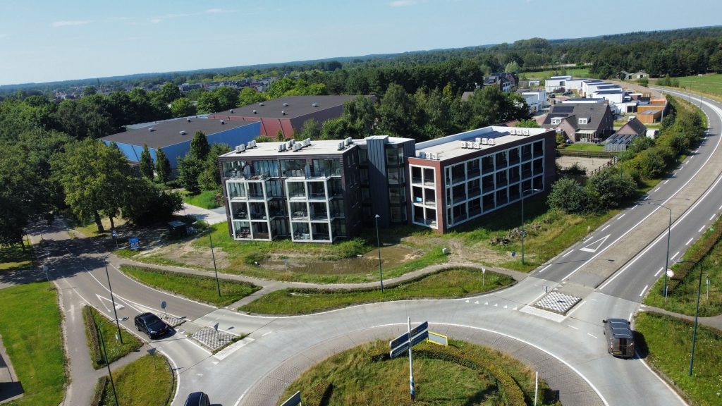 Luchtfoto van rotonde met appartementen en bedrijventerrein.