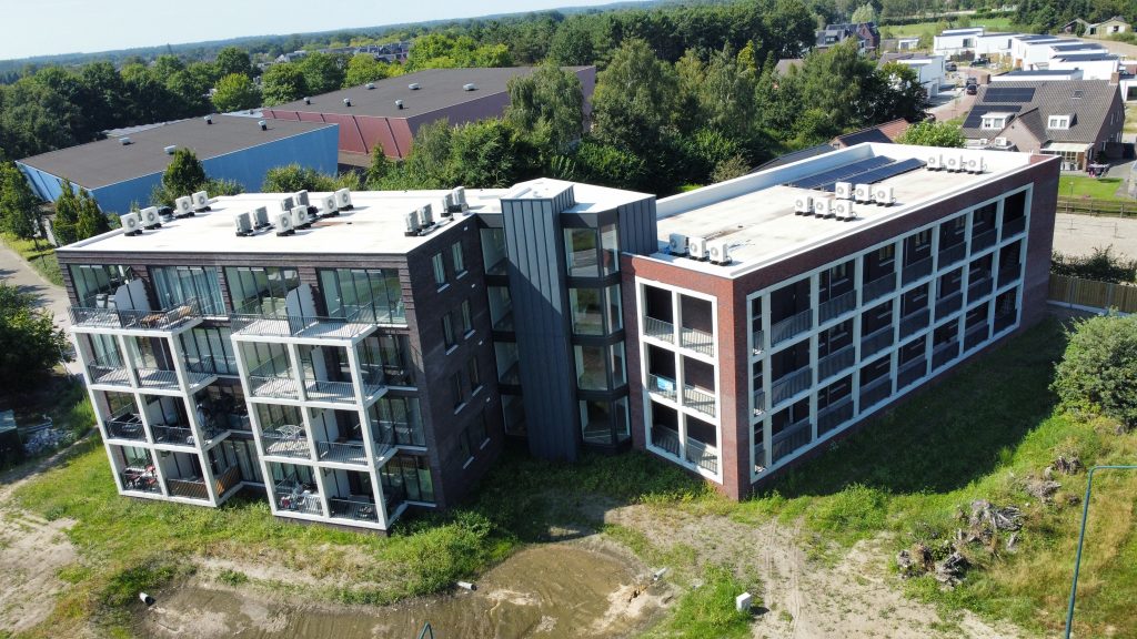 Luchtfoto van een modern appartementsgebouw in groen gebied.