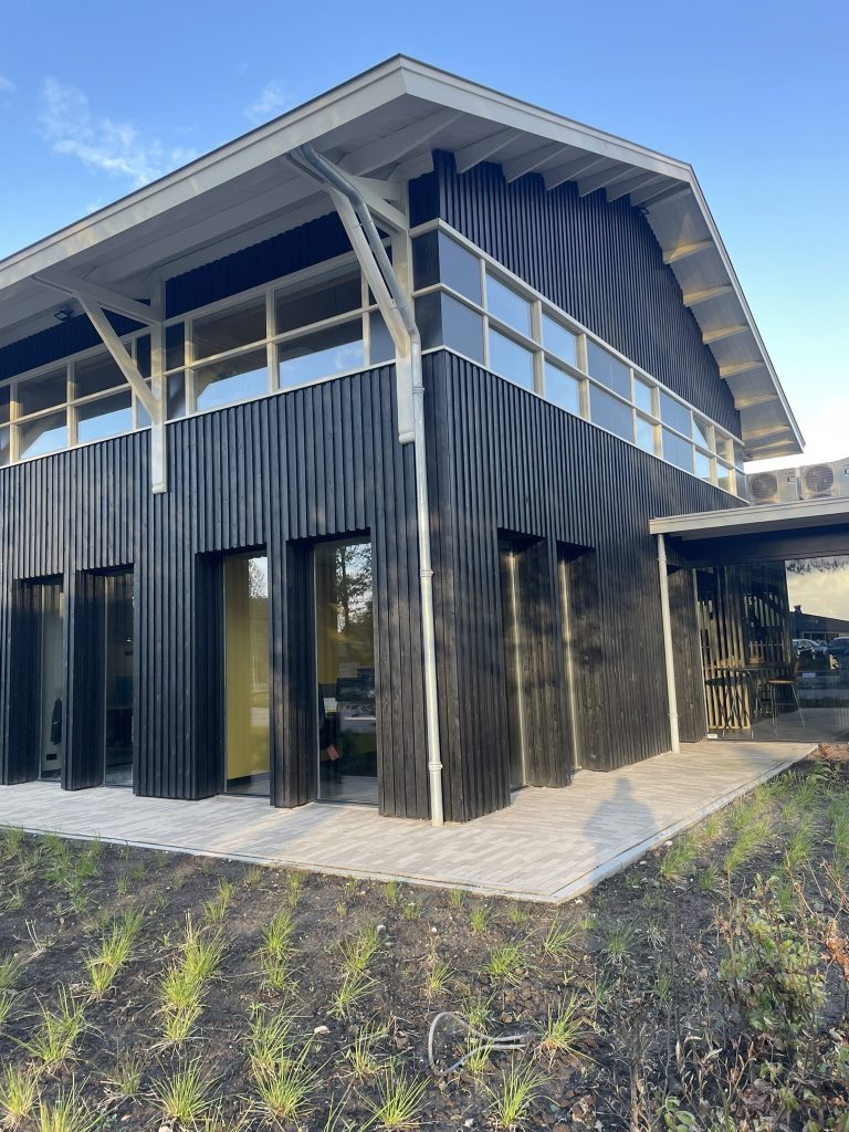 Modern, zwart houten gebouw met grote ramen.